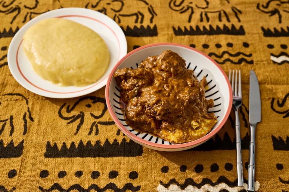 Foutou Sauce Graine traditionnel ivoirien — sauce onctueuse à base de noix de palme avec bœuf, crabe et escargots, servi avec foutou banane-igname pilonné à la main — Restaurant Mauya Lyon 3